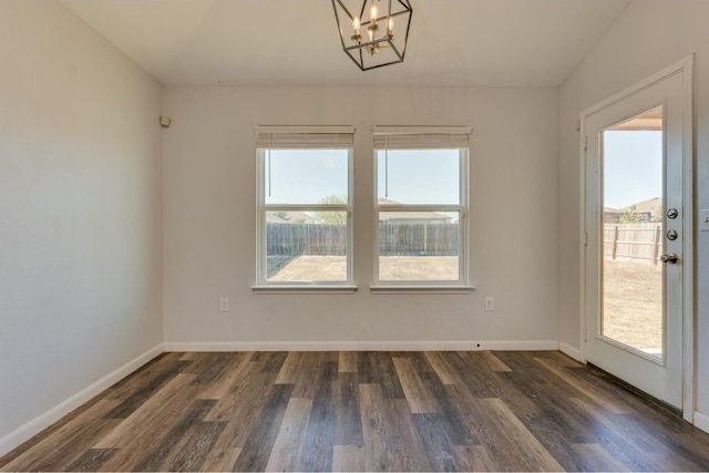 unfurnished room with a wealth of natural light, dark hardwood / wood-style flooring, and a chandelier