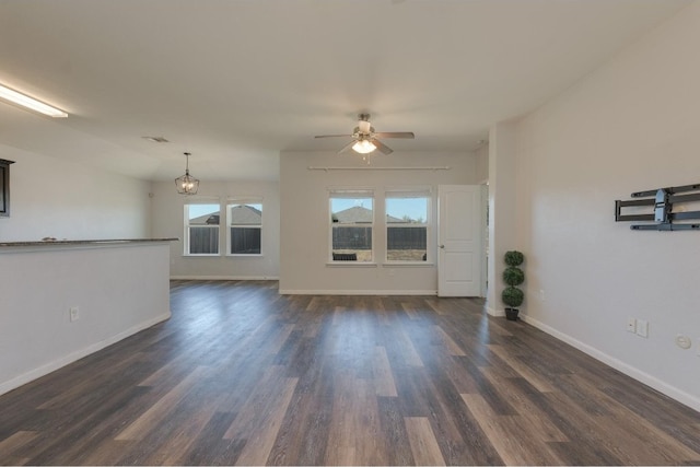 unfurnished living room featuring ceiling fan with notable chandelier, dark wood-type flooring, and vaulted ceiling