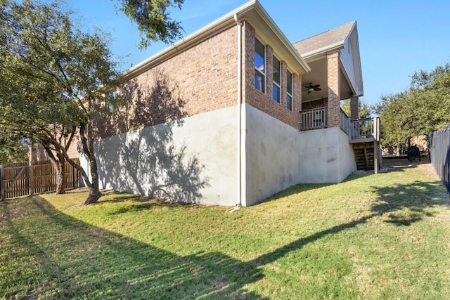 view of side of property with ceiling fan and a yard