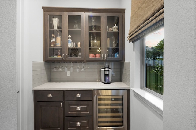 bar featuring tasteful backsplash, wine cooler, and dark brown cabinets