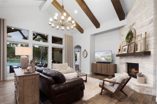 living room featuring a stone fireplace, high vaulted ceiling, dark hardwood / wood-style floors, and an inviting chandelier