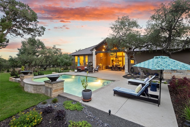 pool at dusk with outdoor lounge area, a patio, and a hot tub