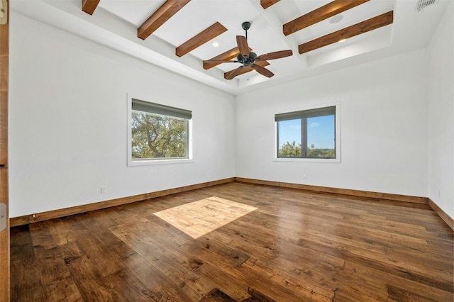 empty room with beam ceiling, dark wood-type flooring, and a wealth of natural light