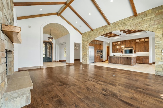 unfurnished living room with beamed ceiling, light hardwood / wood-style floors, and high vaulted ceiling