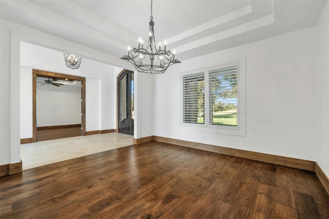 unfurnished room featuring hardwood / wood-style floors, ceiling fan with notable chandelier, and a tray ceiling