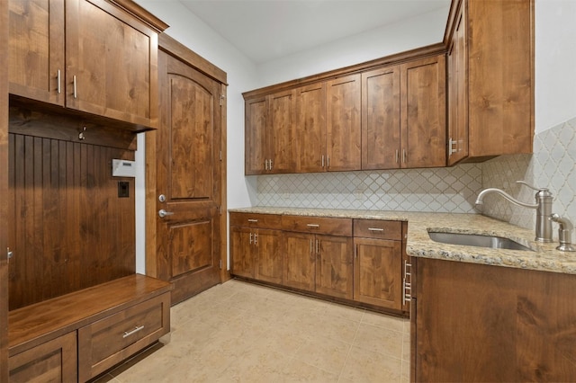 kitchen with decorative backsplash, light stone counters, and sink