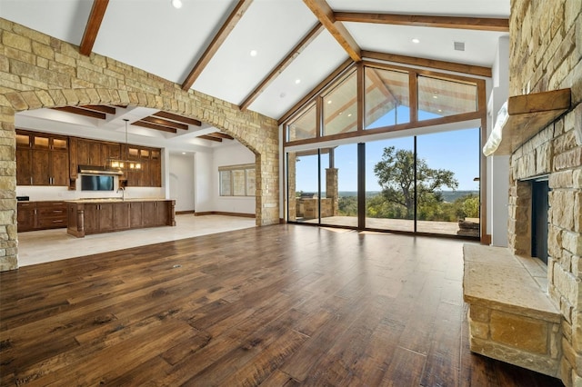 unfurnished living room with hardwood / wood-style floors, high vaulted ceiling, and beam ceiling