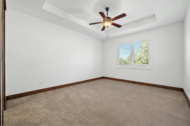 unfurnished room with carpet floors, a tray ceiling, and ceiling fan