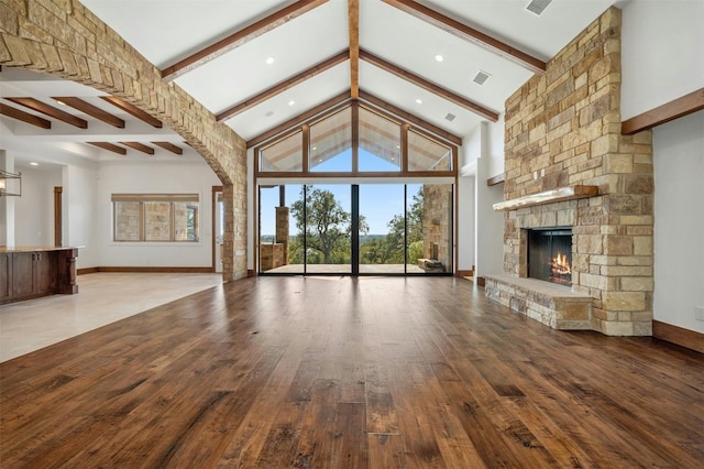 unfurnished living room featuring a fireplace, high vaulted ceiling, wood-type flooring, and beamed ceiling