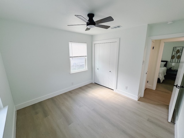 unfurnished bedroom with ceiling fan, a closet, and light hardwood / wood-style flooring