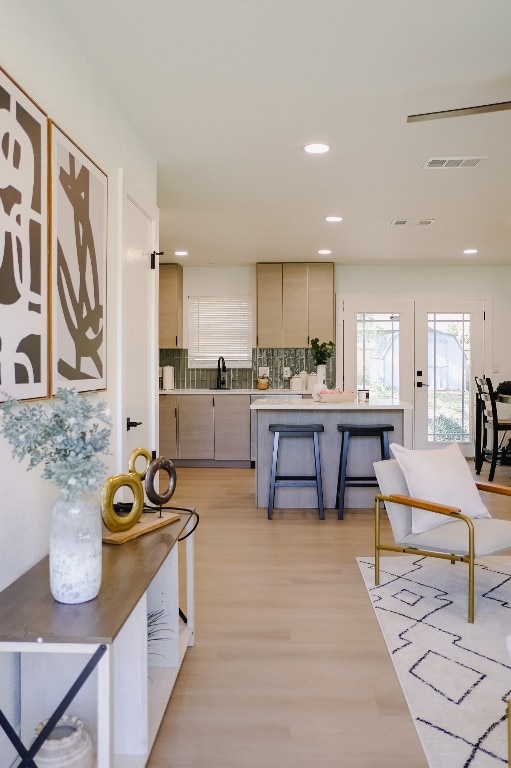 kitchen with backsplash, sink, a breakfast bar area, and light wood-type flooring