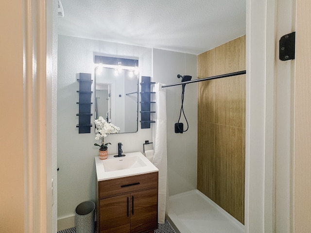 bathroom featuring a tile shower, vanity, and a textured ceiling