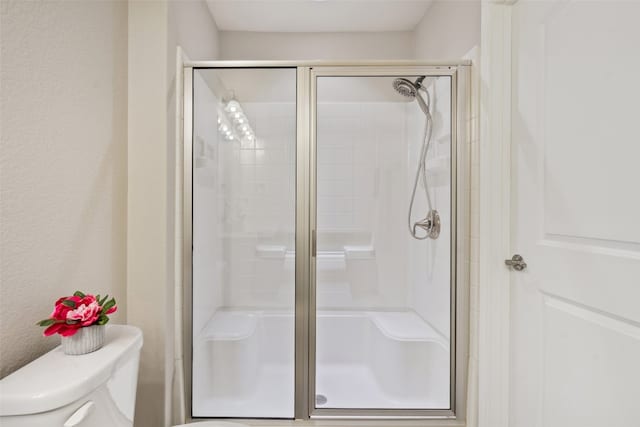 bathroom with toilet and a shower with shower door