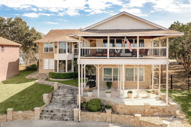 rear view of property with a yard, a balcony, and a patio area