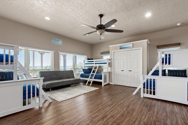 bedroom with ceiling fan, dark hardwood / wood-style flooring, a textured ceiling, and a closet