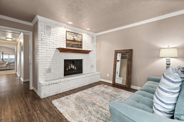 living room featuring a textured ceiling, a fireplace, ornamental molding, and dark wood-type flooring