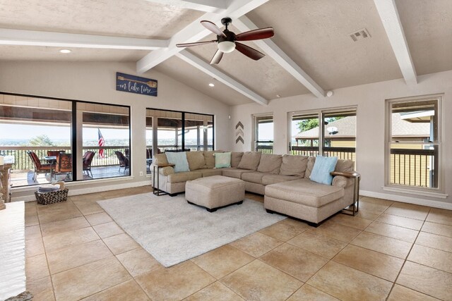 tiled living room featuring vaulted ceiling with beams, ceiling fan, and a textured ceiling