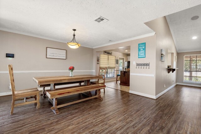 dining room with a textured ceiling, lofted ceiling, dark hardwood / wood-style floors, and ornamental molding