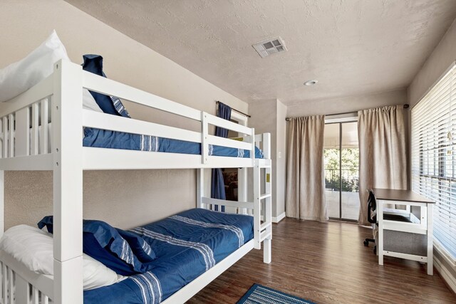 bedroom featuring multiple windows, dark wood-type flooring, and a textured ceiling