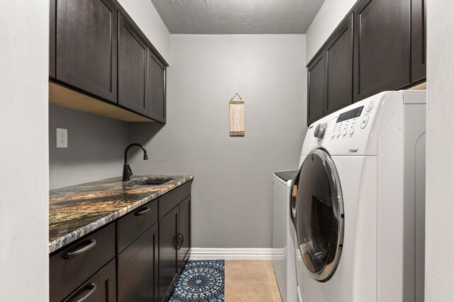 laundry room featuring sink, cabinets, washing machine and dryer, a textured ceiling, and light tile patterned flooring