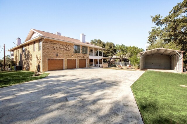 view of front of house with cooling unit, a garage, a front yard, and a carport