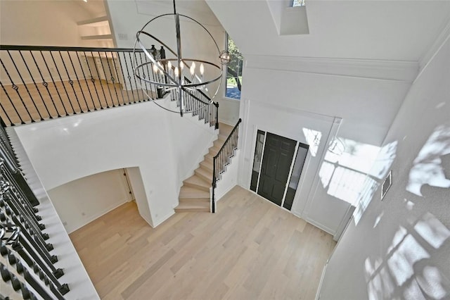 entryway featuring a notable chandelier, light hardwood / wood-style floors, and a towering ceiling