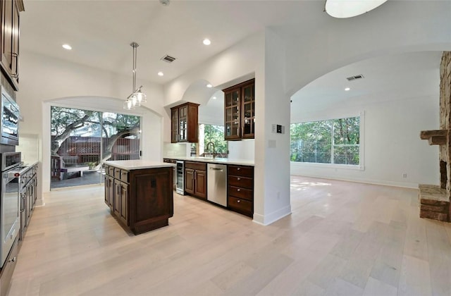 kitchen featuring dark brown cabinetry, dishwasher, a center island, and hanging light fixtures