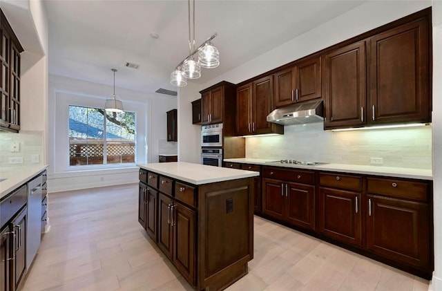 kitchen with a center island, dark brown cabinetry, hanging light fixtures, and tasteful backsplash