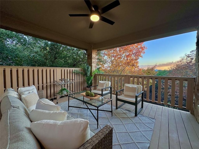 deck at dusk featuring ceiling fan and an outdoor living space