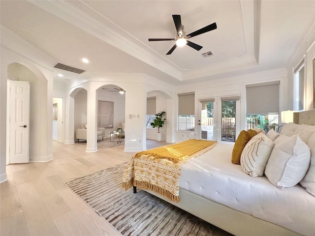 bedroom featuring access to exterior, ceiling fan, french doors, light hardwood / wood-style flooring, and a tray ceiling