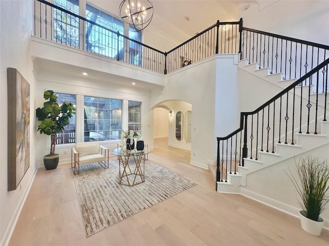 entrance foyer with hardwood / wood-style flooring, a notable chandelier, and a towering ceiling