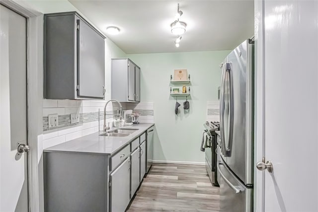 kitchen featuring sink, decorative backsplash, gray cabinets, light hardwood / wood-style floors, and stainless steel appliances