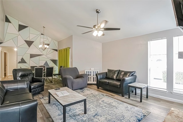 living room featuring hardwood / wood-style floors, ceiling fan with notable chandelier, and vaulted ceiling