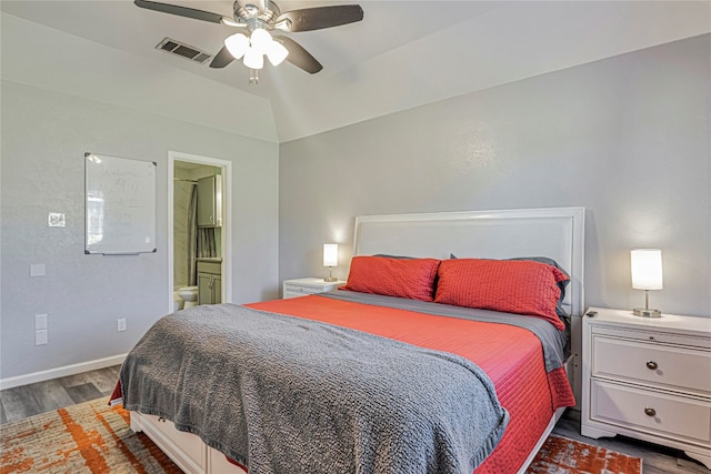 bedroom featuring dark hardwood / wood-style floors, ceiling fan, vaulted ceiling, and ensuite bath