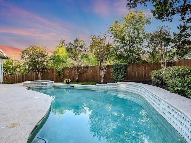 pool at dusk featuring an in ground hot tub