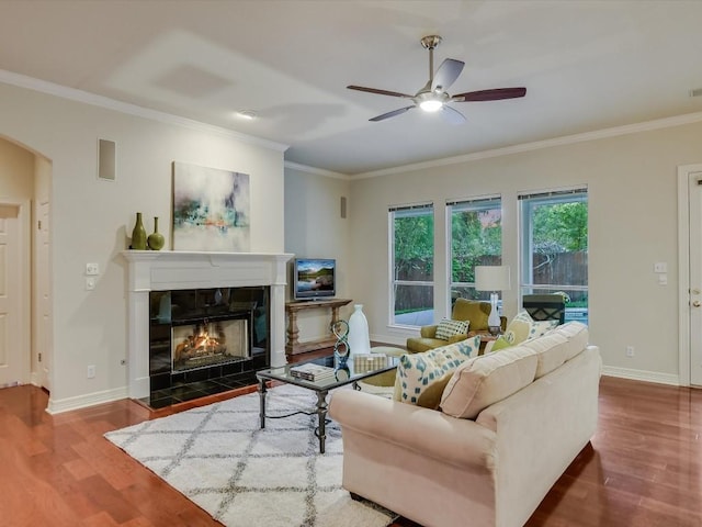 living room with crown molding, wood-type flooring, and a tiled fireplace