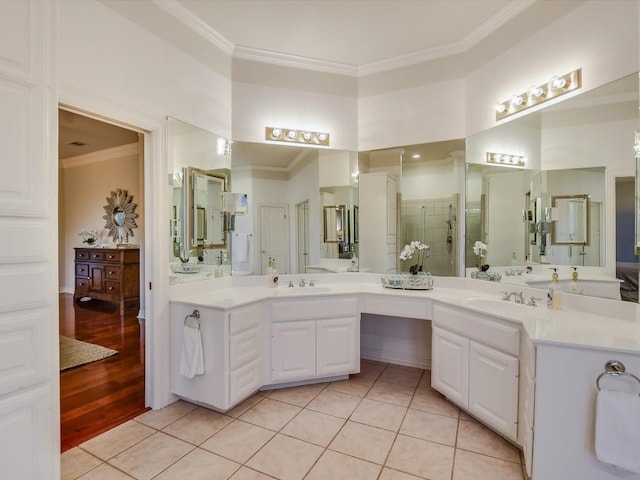 bathroom featuring tile patterned floors, ornamental molding, a shower with door, and vanity