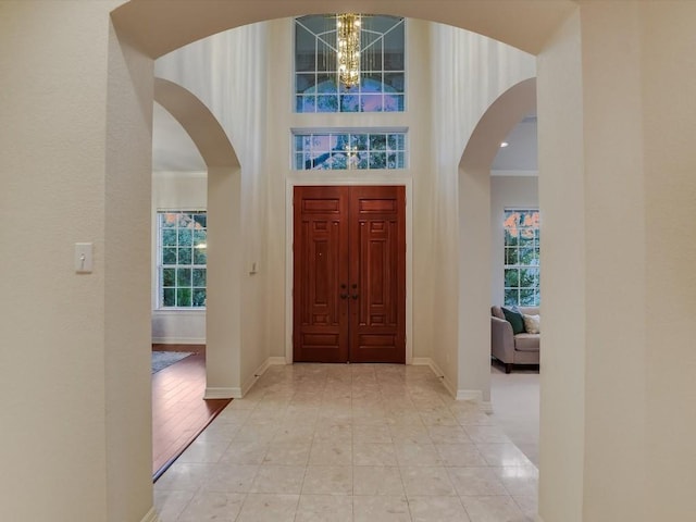 entryway featuring an inviting chandelier, light tile patterned floors, and a high ceiling