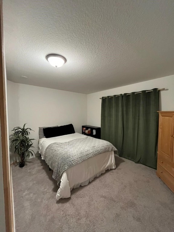 bedroom with a textured ceiling and light colored carpet