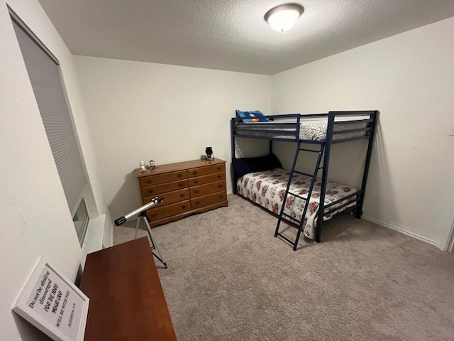 bedroom with light colored carpet and a textured ceiling