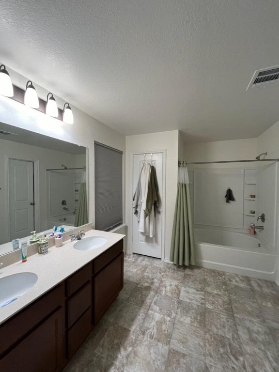 bathroom with shower / bath combo with shower curtain, vanity, and a textured ceiling