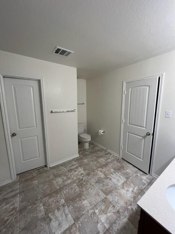 bathroom featuring vanity, toilet, and a textured ceiling