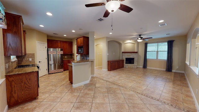 kitchen featuring light stone countertops, ceiling fan, decorative backsplash, light tile patterned floors, and appliances with stainless steel finishes