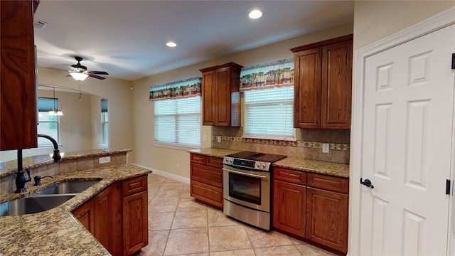 kitchen with stainless steel range with electric stovetop, sink, decorative backsplash, ceiling fan, and light stone countertops