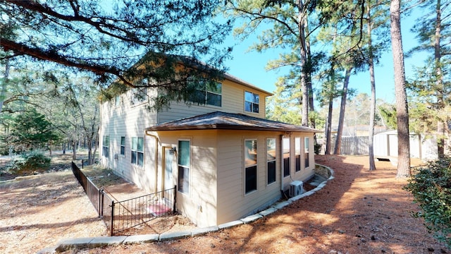 view of side of home with central AC and a storage shed