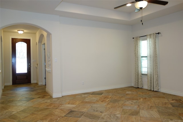 foyer entrance with ceiling fan, a healthy amount of sunlight, and a raised ceiling