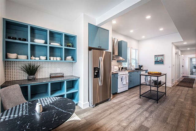 kitchen with hardwood / wood-style floors, stainless steel fridge with ice dispenser, white gas range oven, and wall chimney range hood