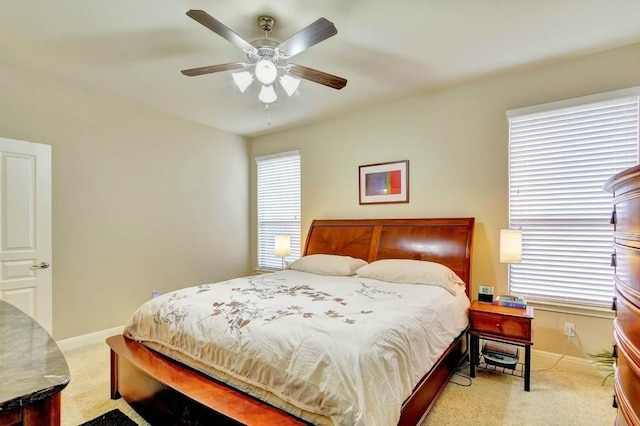 bedroom with multiple windows, light colored carpet, and ceiling fan