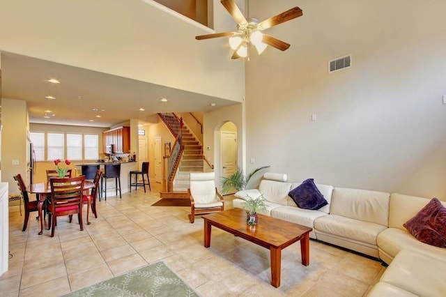 living room featuring light tile patterned flooring, ceiling fan, and a high ceiling