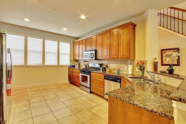 kitchen featuring light tile patterned floors, sink, stainless steel appliances, and stone countertops